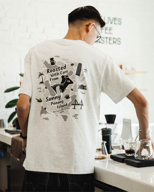 Barista wearing a merch t-shirt with graphics and text, standing in a coffee bar at Nine Lives Coffee Roasters.